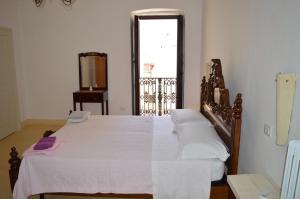a bedroom with a large bed with white sheets and a window at Corte Sant'Anna in Galatone
