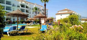 a pool with chairs and umbrellas next to a hotel at DiCaprio - Sunset Ritual incl I by MovieStar Holidays in Mijas Costa