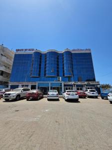 Un gran edificio con coches aparcados en un estacionamiento. en فندق سماء الإمارات, en Khawr Maksar