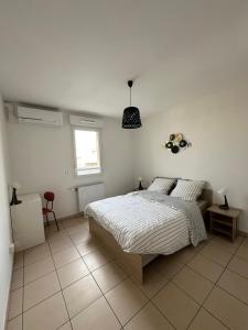 a white bedroom with a bed and a window at Appartement T3 in Villeurbanne