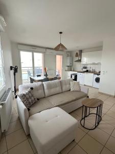 a living room with a white couch and a kitchen at Appartement T3 in Villeurbanne
