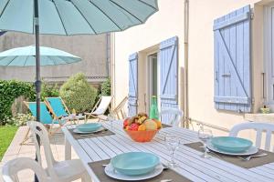 a table with a basket of fruit and a blue umbrella at Charmante Maison Familiale in Ploubalay +16 photos