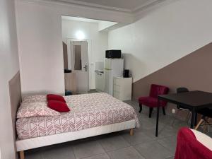a bedroom with a bed with red pillows and a table at Studio SN1 - Centre-Ville Meaux - Proche Disneyland in Meaux