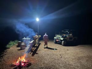 two men standing next to a camp fire at night at Misty Nature Resort in Ratnapura