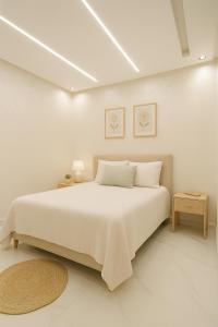 ein weißes Schlafzimmer mit einem großen Bett und einem Teppich in der Unterkunft aslan appart in Martil