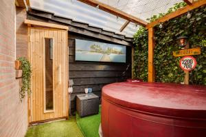a room with a tv and a large red stool at Wellness apartment Apeldoorn with Sauna and Jacuzzi in Apeldoorn