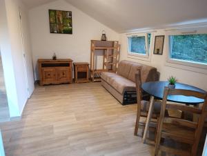 a living room with a couch and a table at studio cosy en pleine forêt in Anduze
