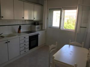 a kitchen with white cabinets and a table and a microwave at DUPLEX 3 DORMITORIOS en LA MANGA in San Javier