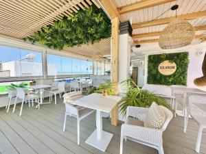 a restaurant with white tables and chairs on a deck at Hotel Apartamentos Marina Luz in Chipiona