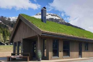 a building with a grass roof with a snow covered mountain at 2 cabins surrounded by beautiful nature in Stryn