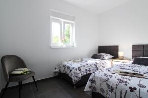 Un dormitorio con dos camas y una silla y una ventana. en Fly in Apartment, en Čilipi