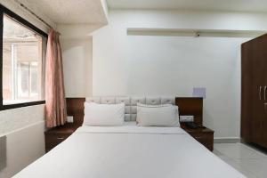 una camera da letto con un grande letto bianco con una finestra di Hotel Paradise a Jamnagar