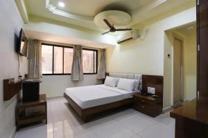 una camera da letto con un letto e una televisione di Hotel Paradise a Jamnagar