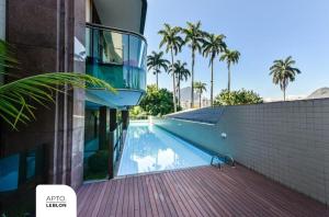 una piscina junto a un edificio con palmeras en O Melhor Residencial com Serviços do Leblon, en Río de Janeiro