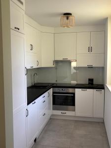 a kitchen with white cabinets and a black counter top at Apartament Grzmięca pl in Grzmięca