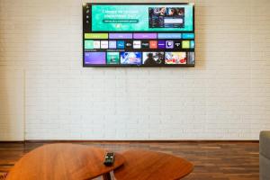 een televisie aan de muur met een houten stoel bij Cozy 2BR Relaxing Vibe in Lima