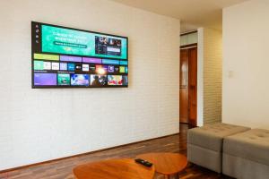 een woonkamer met een bank en een tv aan de muur bij Cozy 2BR Relaxing Vibe in Lima