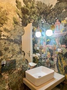 ein Badezimmer mit einem weißen Waschbecken und einem Wandgemälde in der Unterkunft Little Heaven Apartments in Sibiu