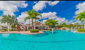 a large swimming pool with palm trees in front of a house at Townhouse Retreat in Riverview