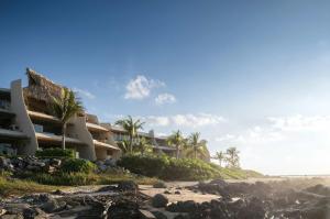 a building on the beach next to the ocean at Punta Majahua by PRC Hospitality in La Majahua