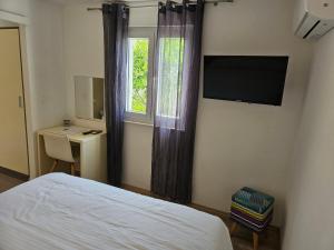 a bedroom with a bed and a window and a television at Apartmani Marinović in Podgora