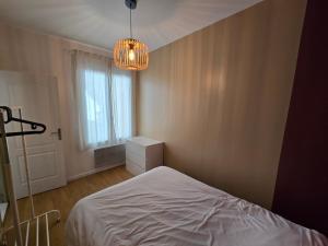 イシー・レ・ムリノーにあるAppartement spacieux 28m2 avec chambre séparéeの白いベッドとシャンデリアのある寝室