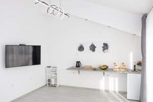 Dieses weiße Zimmer verfügt über einen Tisch und einen TV an der Wand. in der Unterkunft Studio Andrea in Dubrovnik