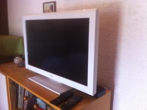 a computer monitor and two remote controls sitting on a shelf at Apartments Renato in Vrboska