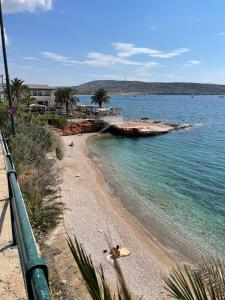 a sandy beach with palm trees and the ocean at Varkiza Beach Entire Apartment in Vari