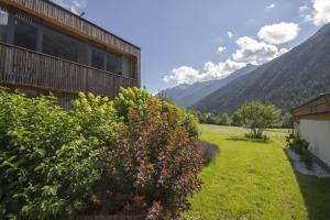 a garden next to a building with mountains in the background at Ferienhaus Alpin, Apartment 1 in Neustift im Stubaital