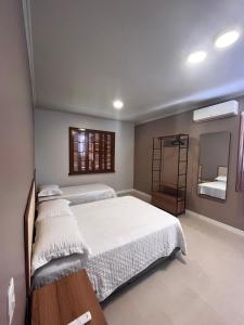 a bedroom with two beds and a mirror at Casa Nona Chema in Bento Gonçalves