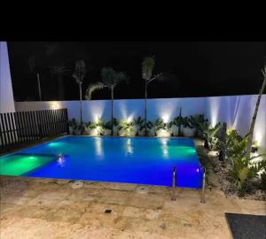 a large swimming pool with blue water at night at Karamelo Tropical Getaway in Santiago de los Caballeros +3 photos