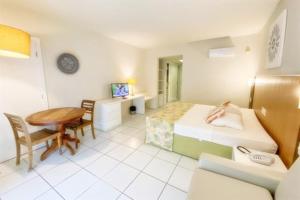 a hotel room with a bed and a desk and a table at Búzios Beach Resort in Buzios +27 photos