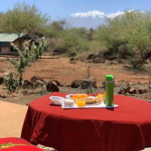 a red table with a plate of food and a green drink at Oldonyo Musa Amboseli Campsite in Rift Valley +34 photos