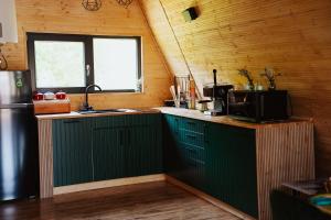 a kitchen with green cabinets and a sink and a window at A-Forest Retreat - David's A-frame in Ocna-Mureşului