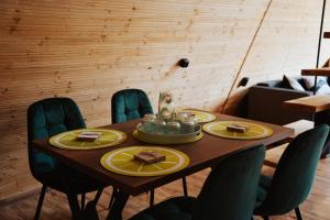 a wooden table with yellow plates on top at A-Forest Retreat - David's A-frame in Ocna-Mureşului