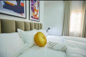 MamaPeridot Apartment Central Area, Abuja的一张白色的床,上面有黄色枕头