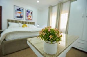 MamaPeridot Apartment Central Area, Abuja的一间卧室，里面有一张床和一张桌子，桌子上摆着一盆植物