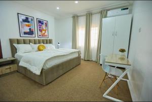 MamaPeridot Apartment Central Area, Abuja的一间卧室，里面有一张床、一张桌子和一把椅子