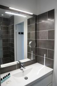a bathroom with a sink and a large mirror at Maison rayons de soleil in Bagnères-de-Bigorre