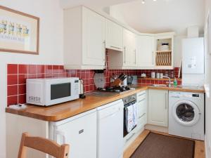 a kitchen with white cabinets and a microwave at Kitcat Cottage in Dartmouth