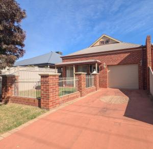 a brick house with a gate and a driveway at Unit in Hovell Street in Yarrawonga