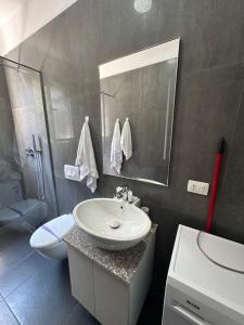 Un baño con lavabo, inodoro y espejo. en Palm Suites Apartments, en Vlorë 30 fotos más