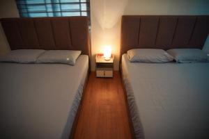 two beds in a room with a candle on a night stand at Meet Up Homestay in Muar in Muar