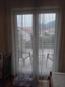 a window with white curtains and a view of a balcony at Apartments Maki 1 in Tivat +5 photos