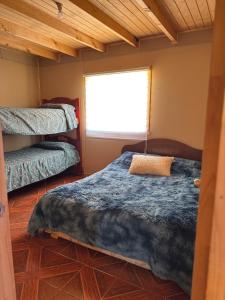 Un dormitorio con dos camas y una ventana. en Cabaña rivera del Captrén, en Curacautín