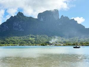 a boat in the water in front of a mountain at Lagoon house between sea and mountain, near Vaitape and Matira in Bora Bora