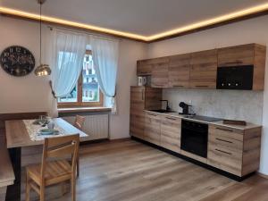a kitchen with wooden cabinets and a table and a counter at Posta Apartments in Colle Santa Lucia