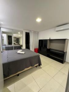 a bedroom with a bed and a flat screen tv at Flat beira mar Olinda Empresarial Jam in Olinda