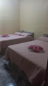 two beds in a room with pink clothes on them at Hotel Atalaia in Vitória da Conquista